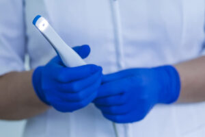 A dentist using an intraoral camera while wearing blue gloves.