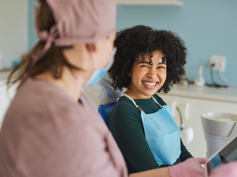 A patient sitting in a dental chair, smiling at the dentist