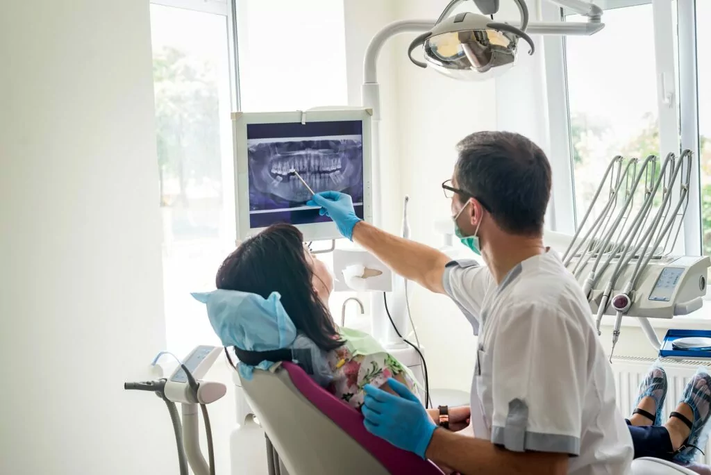 A dentist explaining an X-ray to a patient in a dental chair.