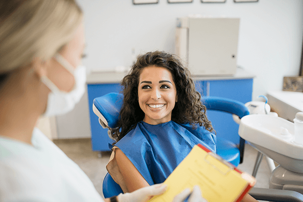 Dental professional consulting with a smiling patient during a routine check-up in a modern clinic.